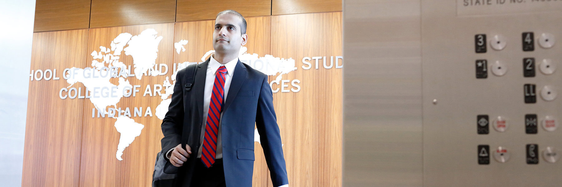 A student dressed in a suit standing in front of an elevator